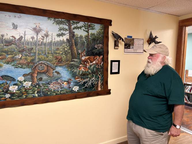 Athol Bird & Nature Club President David Small stands before “Our Unknown Neighbors,” by Bill Fournier, which features 77 different animal species, on display at the Miller River Educational Center. 