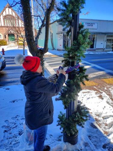 Stephanie McClure wraps scarves around one of the signs downtown for the ‘scarf bombing,’ held on Sunday, Jan. 12.