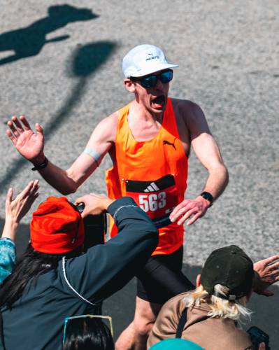 Montague's Michael Keebler high-fives fans while running in the 2025 Boston Marathon on Monday. 