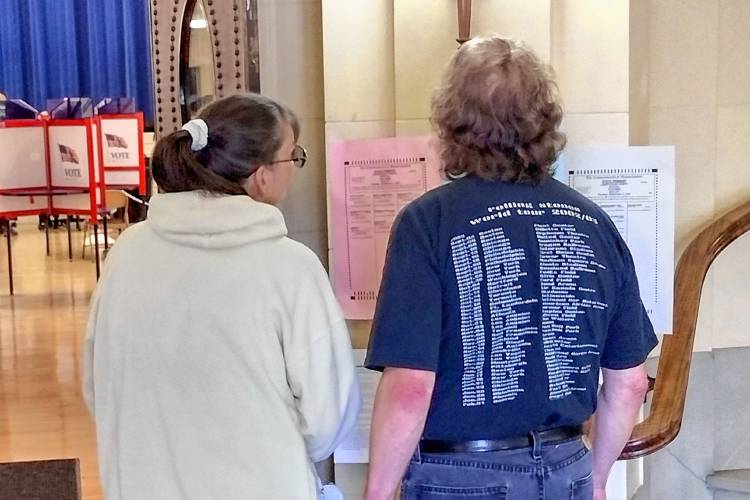 Athol residents Alicia and Jett Murcell check out the sample ballots posted at Athol Town Hall before voting in Tuesday's primary election.