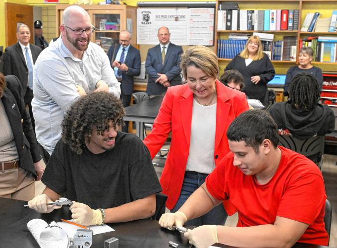 Massachusetts Gov. Maura Healey talks with students in Matt Talbot’s, left, precision measuring instruments class who are using L.S. Starrett slide calibrators to measure metal parts. They are seniors Ethan Okeke, left, and Angel Brito.
