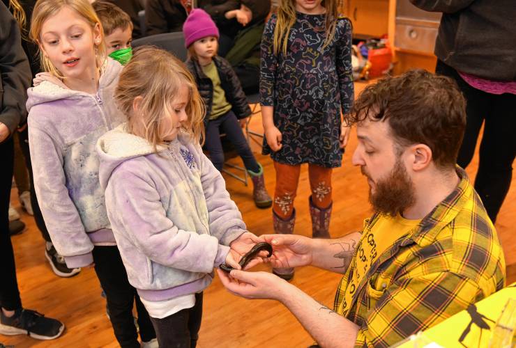 Iris Fisher, 8, and her sister Ivie Fisher, 5, of Petersham, take turns holding an African giant millipede after a presentation by Bryan “Professor Bugman” Man at the Athol Public Library on Thursday, Feb. 22.