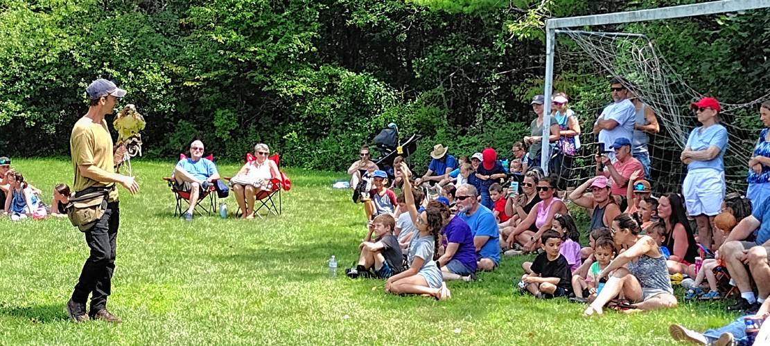 Master Falconer Henry Walters of Monadnock Falconry in Temple, NH, shows Pitch, a red-tailed hawk, to children and adults at Thursday's Falconry in the Park event at Winchendon Community Park.