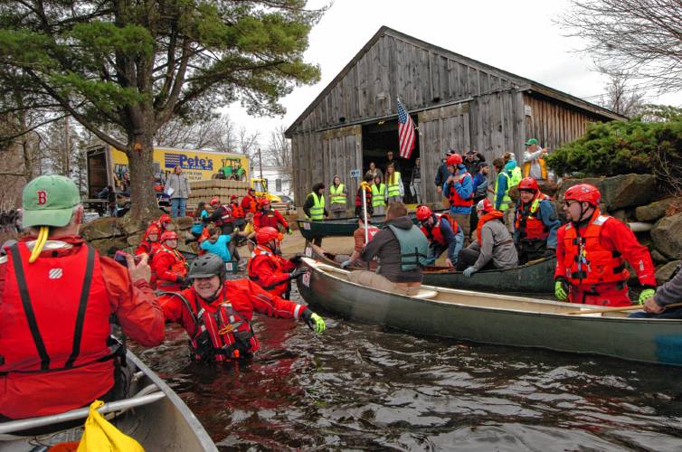 The safety teams help canoes and the paddlers exit the Millers River in Orange on Saturday after the 59th running of the River Rat Race. 