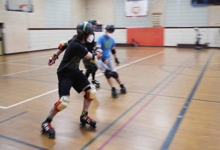 Members of the Pioneer Valley Roller Derby warm up skating around the perimeter of the gymnasium at Franklin Countys YMCA in Greenfield. 