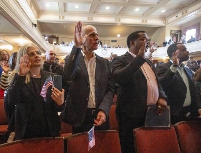 Samia Abboud, left, and Joseph Touma, second from left, both originally from Lebanon, recite the Oath of Allegiance during a naturalization ceremony at Bowker Auditorium, Tuesday, in Amherst.