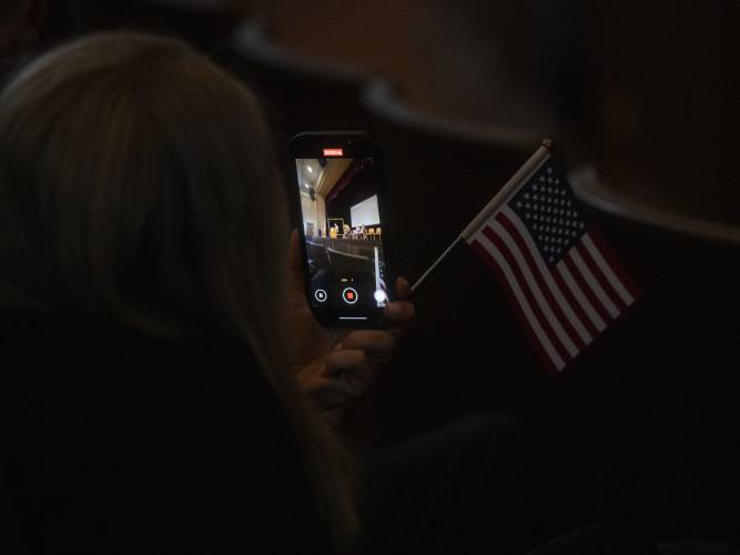 Samia Abboud, originally from Lebanon, films during a naturalization ceremony at Bowker Auditorium, Tuesday, in Amherst.