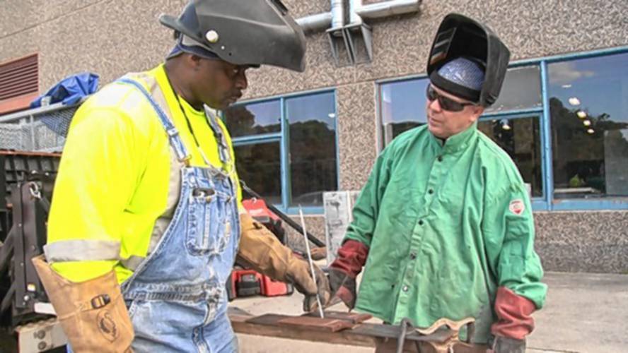 In this still image from the documentary film “Holding Up The Sky,” master welder Ed Jordan, left, teaches apprentice Jimmy Costello. Jordan mentored Costello when they were both in prison in Walpole. Both are featured in “Holding Up The Sky,” which will be shown as part of a program at Orange Innovation Center on June 30.