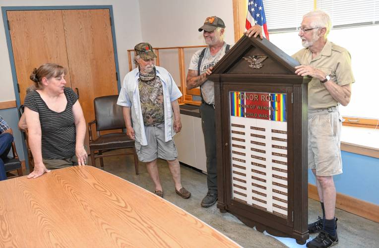 Laurie DiDonato, chair of the Selectboard in Wendell, reads the names of World War II veterans on the refurbished memorial that was returned to Wendell at the Town Offices on Wednesday. Wendell veterans with the sign are Myron Becker, Doug Smith and Josh Heinemann.