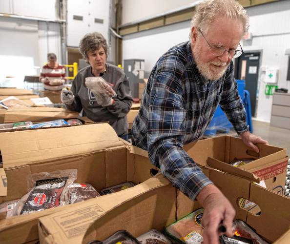 Andrea Leibson and Tome Rees, volunteers at the Food Bank of Western Massachusetts, sort and pack frozen meat to be distributed at one of the many mobile food bank locations. 