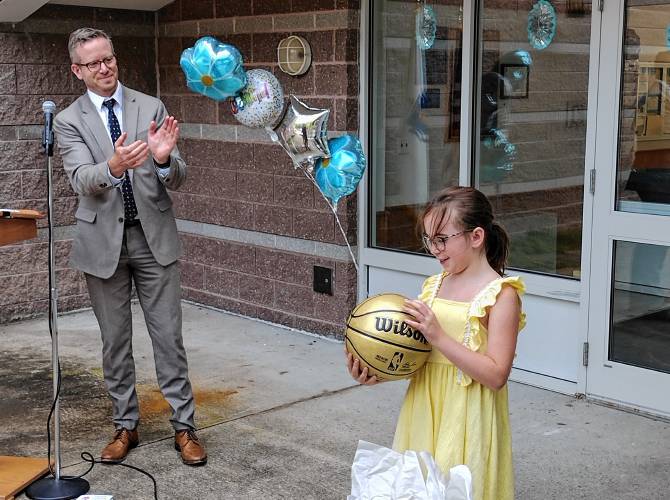 Massachusetts Acting Education Commissioner Russell Johnston applauds after handing a golden Celtics ball to Royalston Community School fifth-grader Maizy DeCosta, an award for the school being in the top 10 to reduce chronic absenteeism over the last academic year. The award ceremony was held on Wednesday, Aug. 14.