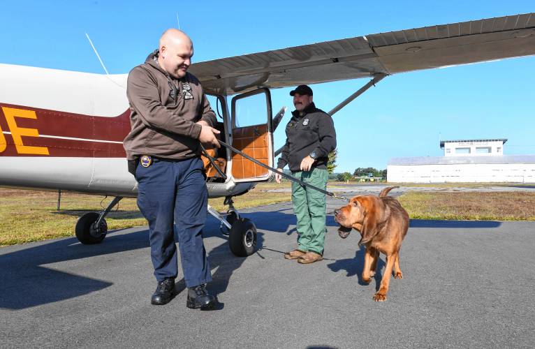 William Figura of the Pawtucket, Rhode Island, Police Department exits a small plane with K-9 Neko at the Orange Airport, where the Northeast Houndsmen organized training exercises on Monday for tracking dogs and their handlers.