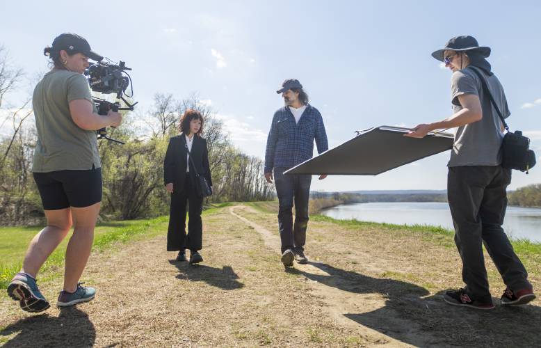 Director of photography Danielle Bryant, left, and key grip Owen King, right, film actors Camryn Mi-Young Kim, second from left, and Gary Gulman, second from right, during production for the short-film “Irving Berlin's View of the East River” near the Connecticut River, Thursday, April 24, 2025, in Hadley.