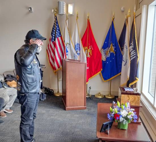 A fellow veteran salutes the remains of William Carver before leaving Friday's funeral service at Massachusetts Veterans Memorial Cemetery.