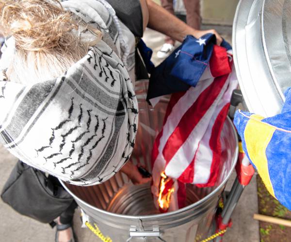 Dodi Melnicoff, left, and Nick Mottern  burn an American  flag in front of Congressman Jim McGovern's Northampton office Tuesday to protest the U.S. government’s complicity in the destruction of Gaza.