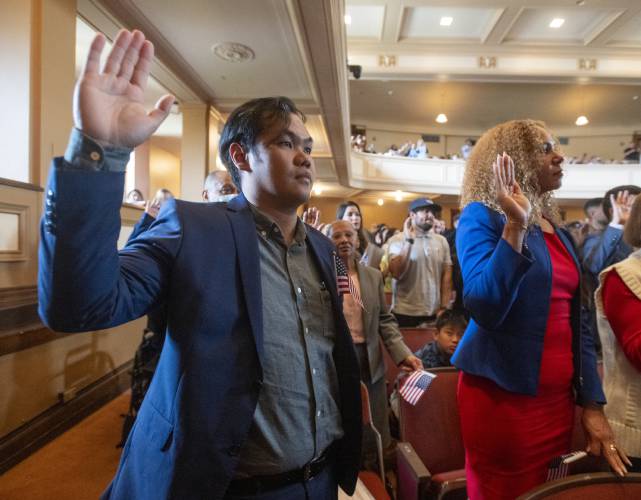 Angelo Mercado, originally from the Philippines, recites the Pledge of Allegiance during a naturalization ceremony at Bowker Auditorium on Tuesday in Amherst.
