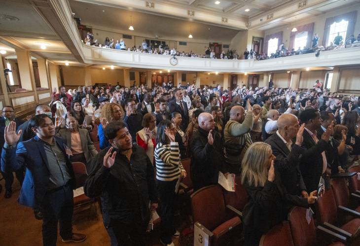 New American citizens recite the Pledge of Allegiance during a naturalization ceremony at Bowker Auditorium, Tuesday in Amherst.