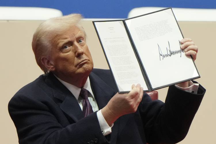 President Donald Trump holds up an executive order after signing it at an indoor Presidential Inauguration parade event in Washington, Jan. 20.