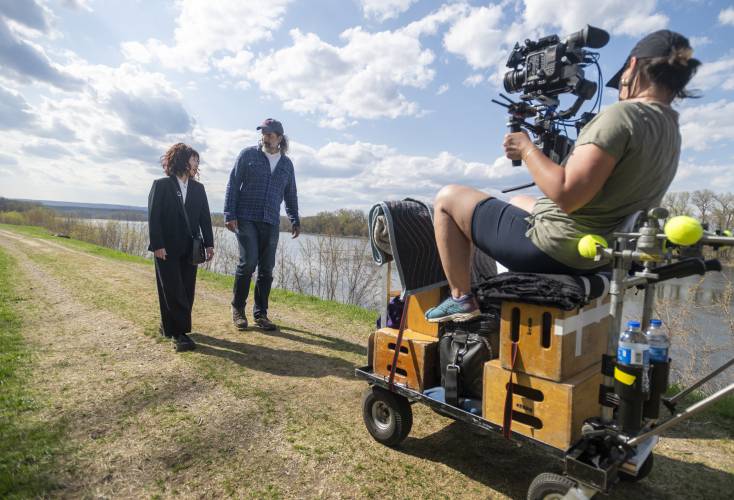 Actors Camryn Mi-Young Kim, left, and Gary Gulman, center, are filmed by Director of Photography Danielle Bryant, right, during production for the short film “Irving Berlin's View of the East River” near the Connecticut River, Thursday, April 24, 2025, in Hadley.