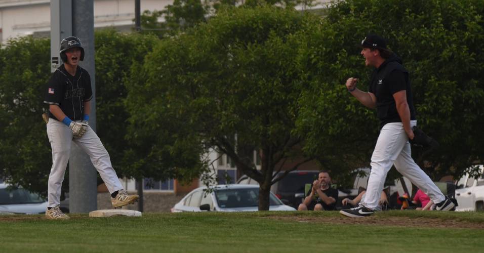 Pioneer’s Brody Welcome, left, and coach Jake Sak, right, celebrate after Welcome drove in a run with a single during the Panthers’ extra innings victory over Georgetown in the MIAA Division 5 Round of 16 on Thursday night in Northfield.