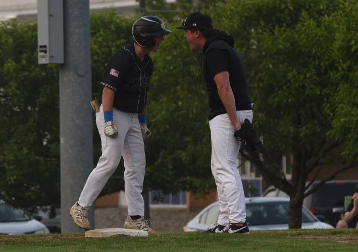 Pioneer’s Brody Welcome, left, and coach Jake Sak, right, celebrate after Welcome drove in a run with a single during the Panthers’ extra innings victory over Georgetown in the MIAA Division 5 Round of 16 on Thursday night in Northfield.