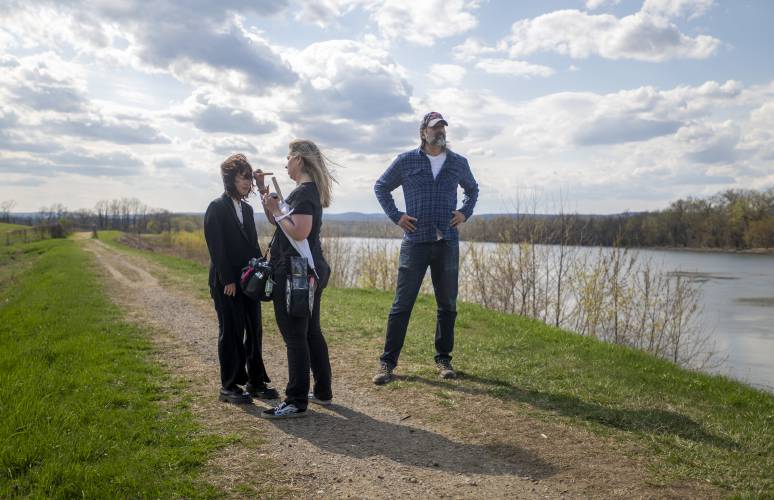 Actor Gary Gulman, right, waits to resume filming as hair and makeup artist Kate Baisley, center, fixes the makeup on actor Camryn Mi-Young Kim, left, during production for the short film “Irving Berlin's View of the East River” near the Connecticut River, Thursday, April 24, 2025, in Hadley.