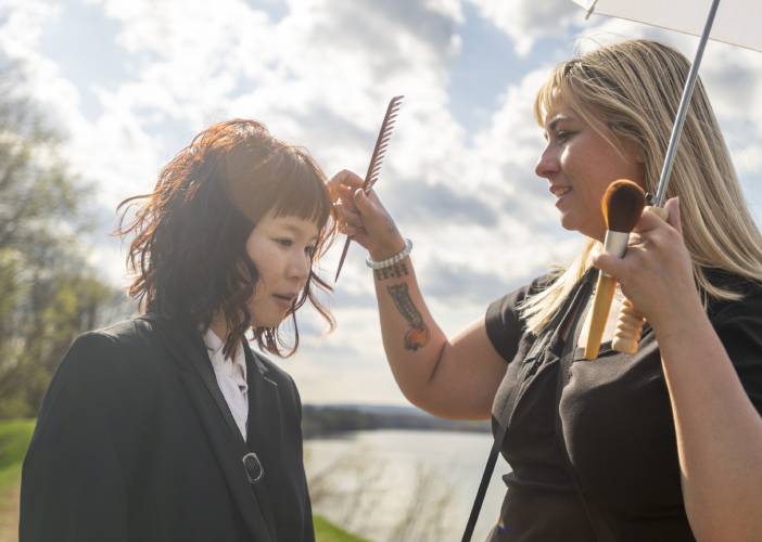 Actor Camryn Mi-Young Kim, left, has their hair fixed by hair and makeup artist Kate Baisley, during production for the short-film “Irving Berlin's View of the East River” near the Connecticut River, Thursday, April 24, 2025, in Hadley.