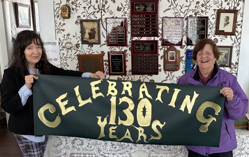 Orange Historical Society Board of Directors member Ann Reed, left, and President Kathryn Schiappa prepare to hang a celebratory banner inside Historical Society.