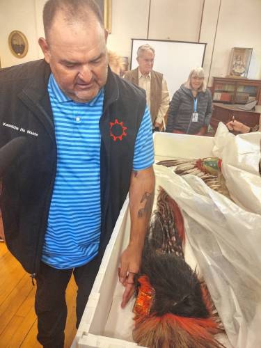 Justin Pourier, Fifth Member and Tribal Historic Preservation Officer of the Oglala Sioux Tribe, examines one of the headdresses being returned by the Woods Memorial Library during a ceremony on Monday, Nov. 11. 
