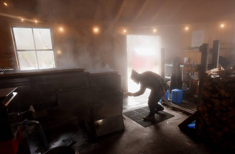 Rich Valcourt of Valcourt Sugar Shack in Petersham is surrounded by steam as his loads wood into his evaporator boiling down sap from his 1,400 taps in the North Quabbin area.
