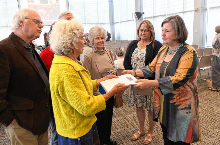 Wendell resident Nina Keller, along with other members of the citizens group No Assault & Batteries, hands state Sen. Jo Comerford, right, a petition with at least 500 signatures against the battery energy storage system proposed for Wendell at Comerford’s People’s Town Hall at Greenfield Community College on Monday.