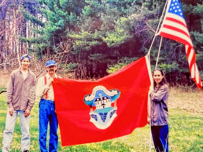 Lydia Musco, with brother Taj and father Tom, unfurl her winning Royalston Town Flag in 1994. The caption on the flag reads, 