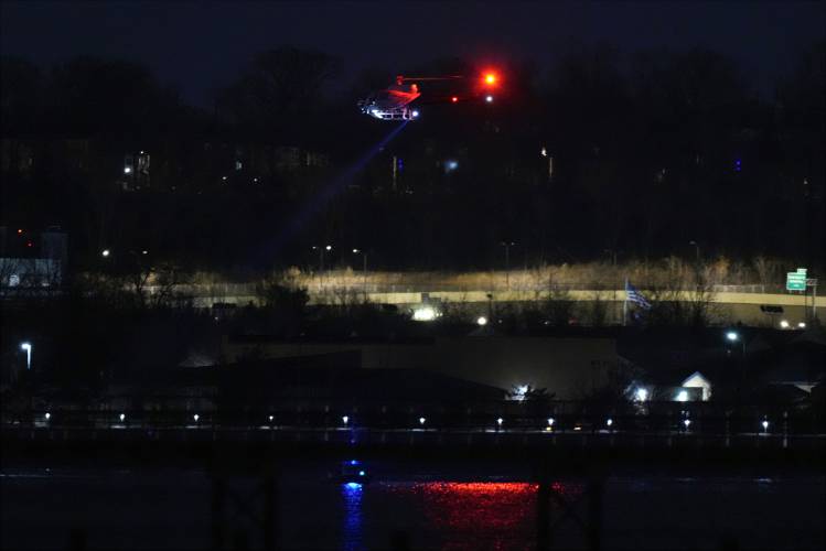 A helicopter uses its searchlight as it flies above the Potomac River near Ronald Reagan Washington National Airport Wednesday, Jan. 29, 2025, in Arlington, Va. (AP Photo/Alex Brandon)